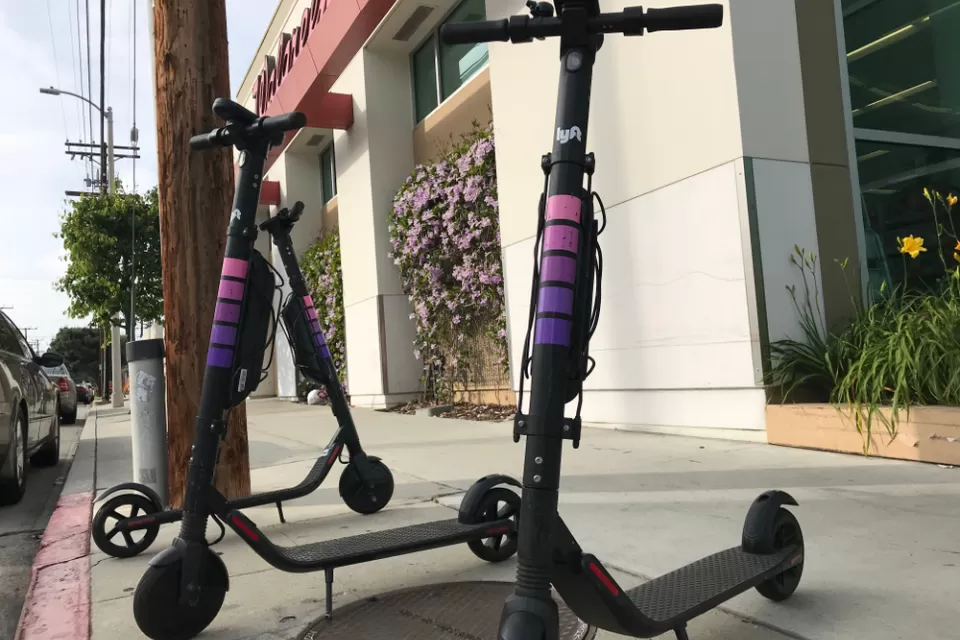 Three Lyft electric scooters parked on a sidewalk in West Los Angeles
